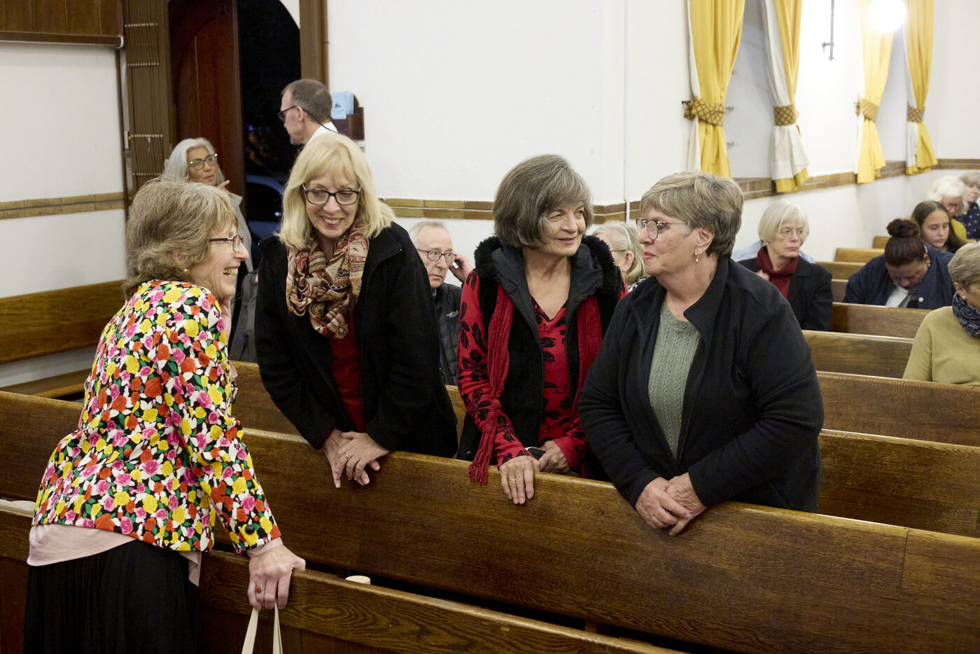 Lidmate gesels en lag saam in die kerkbanke