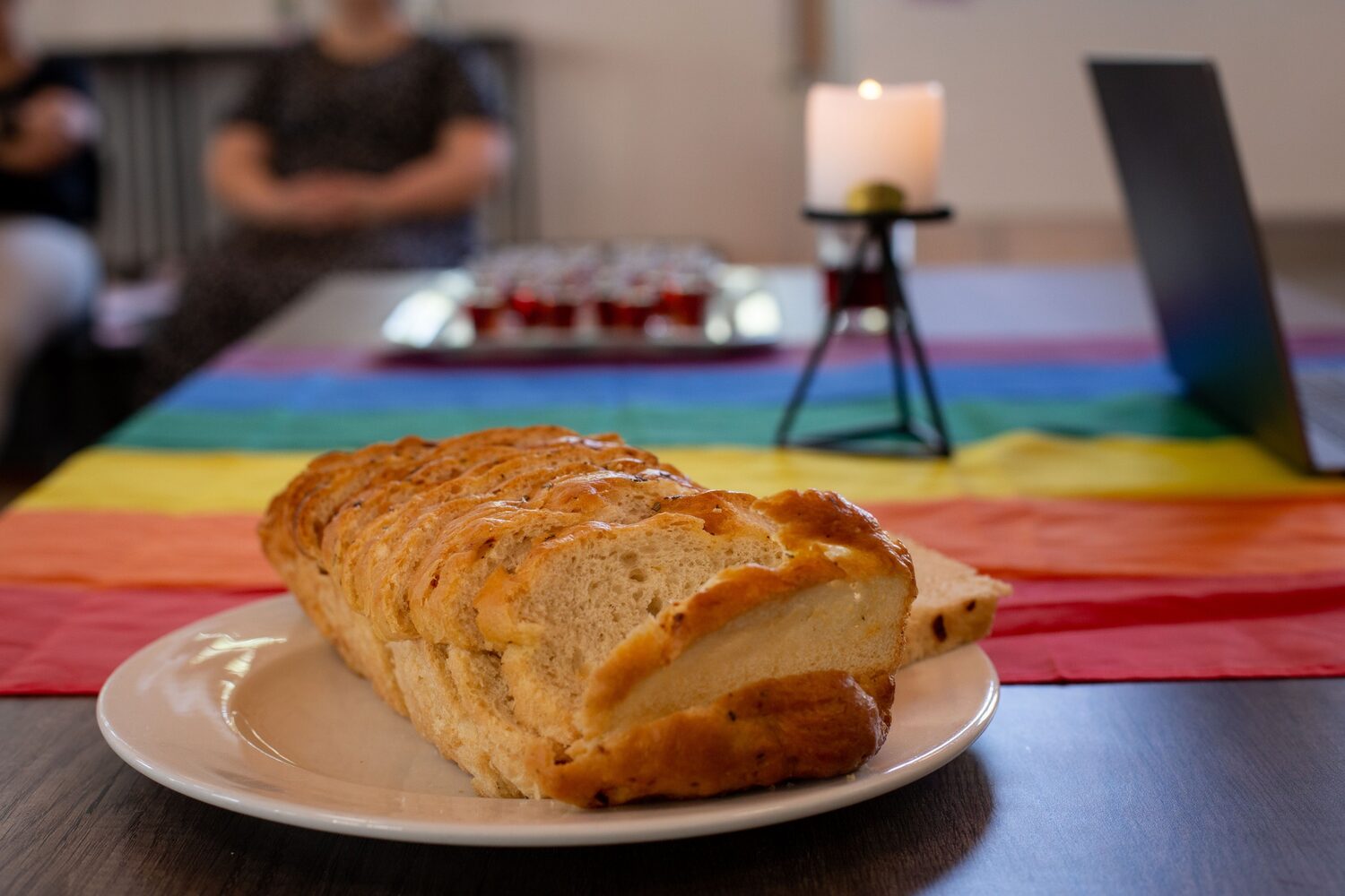 Brood op 'n tafel met 'n reënboog-tafeldoek en 'n kers